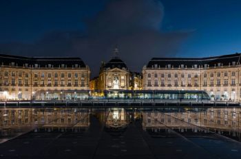 Theater Bordeaux Experience the enchantment of Place de la Bourse at night - Elegant buildings and vibrant lights cast reflections on the water, capturing the lively spirit of the city in a moment of nocturnal beauty