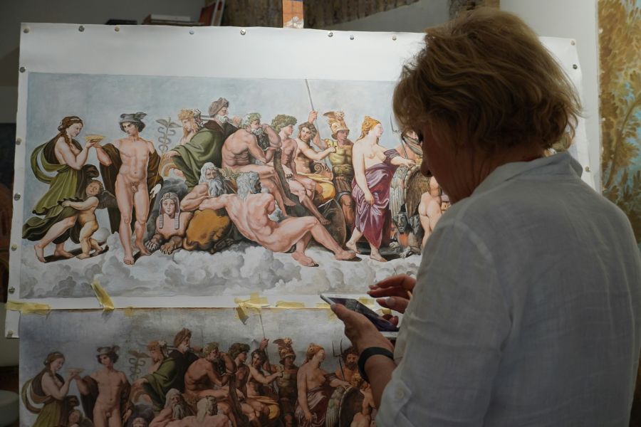 artwork restoration Artist working on a detailed classical painting against a studio background, with various figures depicted on the canvas. 