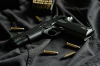 guns A black handgun on black cloth, with ammunition 
