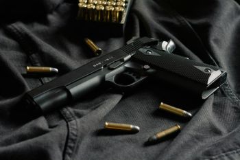 guns A black handgun on black cloth, with ammunition 