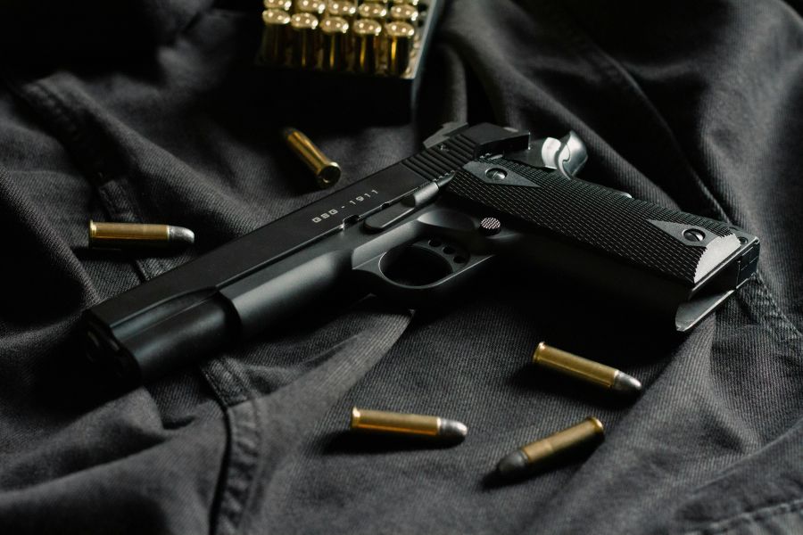 guns A black handgun on black cloth, with ammunition 