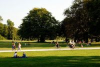 park Many people enjoy the afternoon sun on the meadows of the English Garden, sitting and lying; others walk or ride a bicycle. 