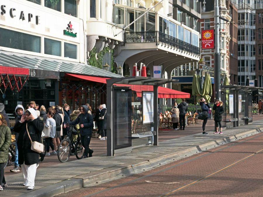 temperatures sunny City photo of the urban square Rembrandtplein in Amsterdam with a lot of walking people in the street on a sunny day in late Winter. In front you see the rais and the tram track. In the background building facades with balconies of restaurants, night clubs and pubs. Free street photography by Fons Heijnsbroek, Netherlands 19 February 2022. // Foto van wandelendmensen op het Rembrandtplein in Amsterdam, ze lopen langs de gevels en terrassen bij de tramhaltes in winter-zon in 2022. Gratis download amsterdam,rembrandtplein,town