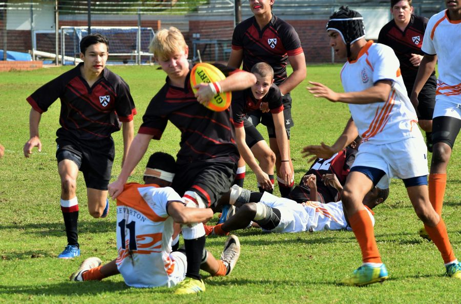 Rugby Match A young man tries to step his opponent (while clutching a rugby ball) during a school boy rugby game as his opponent tries to bring him down at the knees.  team,rugby,sun