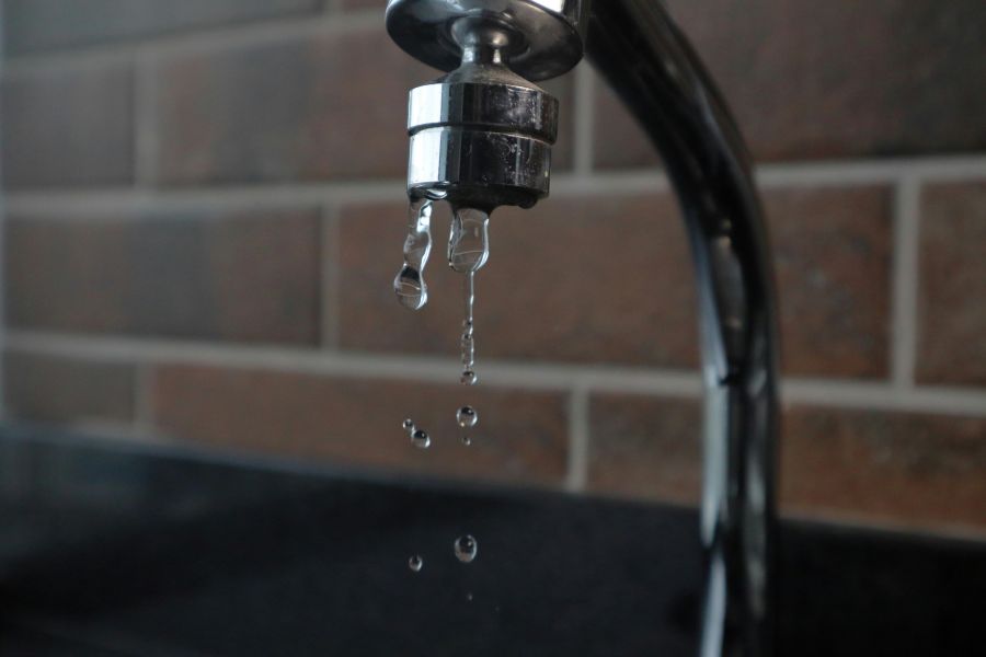 Water waste faucet drops water on brick background 