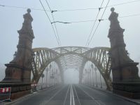 Eric Piolle This is a wonderful foggy morning picture of Zwierzyniecki Bridge
or Most Zwierzyniecki we Wrocławiu.  The bridge disappears into the fog and off into nothingness.  The cables run over head and the street lights are seen in the photos as well.  The train tracks run right down the center of the street.  Wonderful photo. grey,poland,wrocław