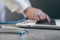 Health Innovation Doctor working with laptop and stethoscope on table, closeup 