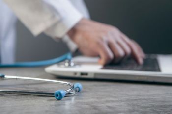 Health Innovation Doctor working with laptop and stethoscope on table, closeup
