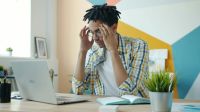 Chronic fatigue Exhausted mixed race man is feeling headache working with laptop in office room touching head suffering from migraine. People and health concept. 