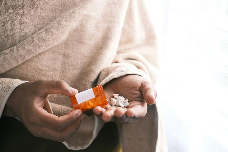 disease man's hand with pills spilled out of the container . 