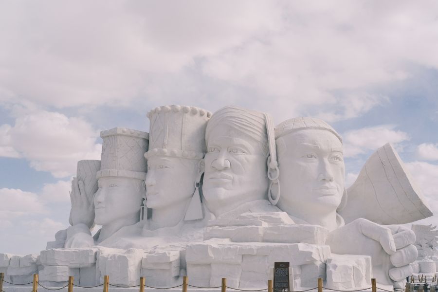 Censorship The photograph captures an intricate snow sculpture resembling the iconic Sphinx and Pyramids of Giza. Against an overcast sky, the detailed sculpture stands as a testament to the enduring allure of ancient Egypt. The grey rectangular areas hint at underlying content, while a rope barrier prevents spectators from touching this winter wonder. 