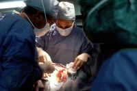 Hospital Surgery Biopsy. A Caucasian woman patient is being operated on. Her nipple is being incised by the surgeon. The male surgeon and an operating room attendant are visible. A surgical biopsy is being performed to determine exact nature of solid tumor. Creator: Linda Bartlett

 surgery,surgeon,biopsy