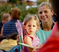 concert children Young child and her mother looking at the camera. Concert in the park. Afternoon sun. Pinks and blues. 