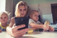 Children at A woman uses smartphone while sitting with children, working mom children,phone,moscow