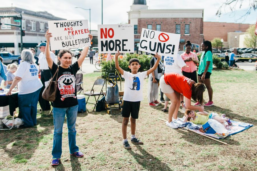 Gun violence A North Texas mother and her son hold protest signs at the March for Our Lives sister rally in Denton, Texas on March 24th, 2018. In the background, volunteers register people to vote. march for our lives,denton,gun laws