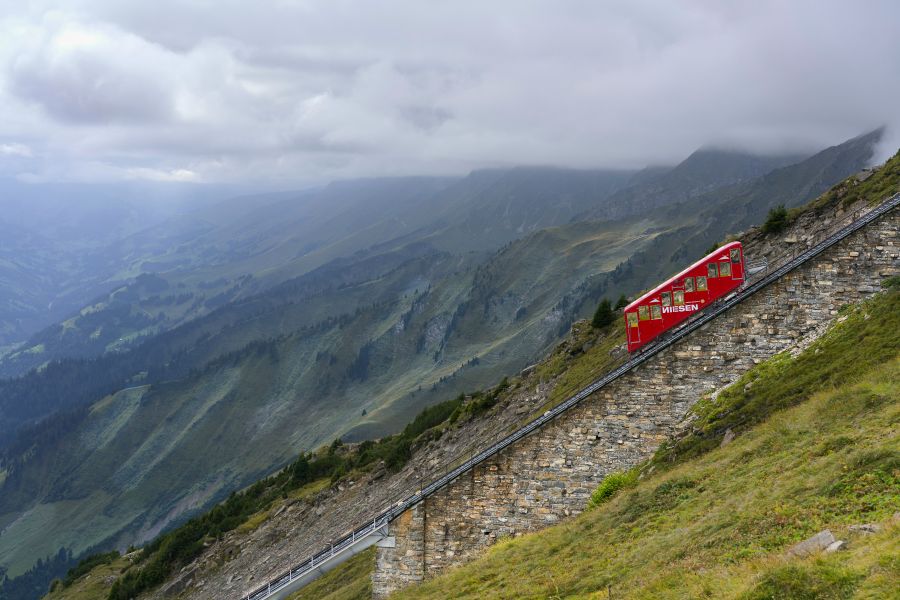 funicular The funicular departs from Mülenen for a spectacular ride up the steep slope to the top of Mount Niesen, at an altitude of 2362 m. From there we afford a magnificent 360° view over Thunersee, the Kandertal, the cities of Spiez, Thun and Interlaken, and the rest of the Bernese Alps. The funicular runs on steep metal rails, but there are no cogs. The railway is split into two sections. One from Mülenen to Schwandegg (max slope 66%), and another from Schwandegg to Niesen Kulm (max steepness 68%). T 