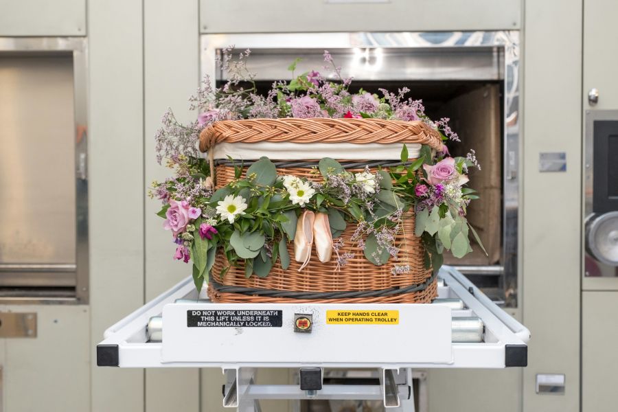 Cremation A willow coffin decorated with flowers in front of a cremator. 