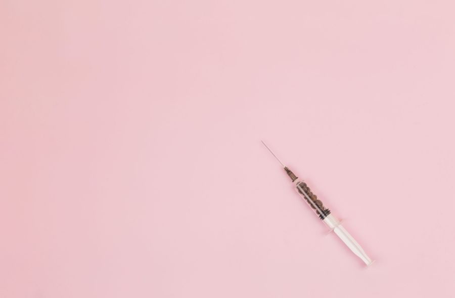 addiction healthcare Transparent syringe with coffee beans inside on a pink background. View from above. Advertising. Place for an inscription. The medicine. Coffee. Intravenous coffee. Syringe. Kofenin. Energy. injection,grey,brown