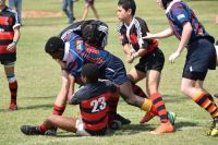 Rugby tackle A determined youth, clutching a rugby ball pushes his way through his adversary's to gain ground, despite the other team tackling him and pulling him back.  development,club rugby,youth