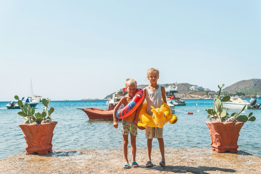 Vacation activities two children with swimming toys on the shore in sunny day vacation,transportation,boat