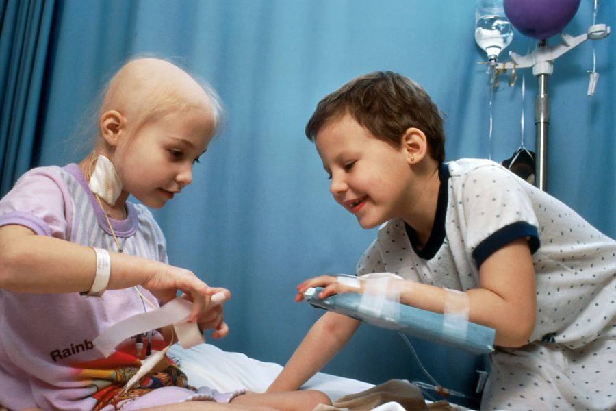 Rare disease Two young girls with acute lymphocytic leukemia (ALL) receiving chemotherapy. The girl on the left has an IV tube in the neck, the other girl's IV is in her arm. They are sitting on a bed and are demonstrating some of the procedures and techniques used with chemotherapy. patient,hospital,disease