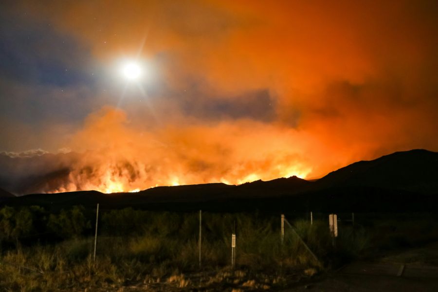 Wildfire evacuation California wildfire with glowing orange smoke in the Sierra Nevada mountains. 