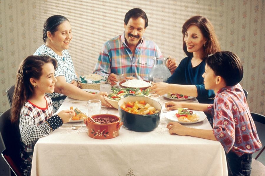 family dinner Family Eating Meal. A Hispanic family (male adult, two female adults, female child, and male child) enjoy a meal at the dinner table. 