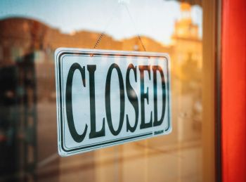 School Closure The sun had just tipped beneath the buildings across the street, and the town was beginning to settle into dusk. This sign stood boldly out from the sharp red of the doorframe and the soft gold light that surrounded me.
