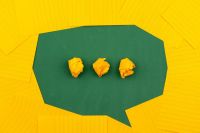 Communication orange sheets of paper lie on a green school board and form a chat bubble with three crumpled papers. email,speak to us,contact us