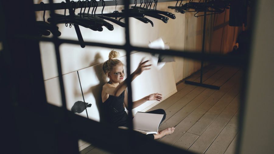 Teenage struggle Young teenage girl dancer crying and tearing book sits on floor in hall 