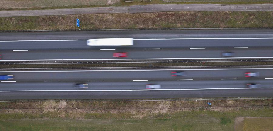 Road safety Captured from above, this image portrays the dynamic flow of traffic on a highway. Vehicles blur into streaks of color, illustrating the pace of life on the road. The patterns of the lanes and the sense of movement offer a glimpse into daily commutes and the arteries of transportation. 
