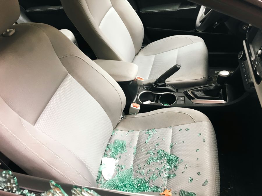Car theft the aftermath of a car break-in, with shattered glass scattered across the passenger seat. The side window has been broken during a theft. 