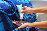 Sunscreen dispenser Squeezing CBD lotion into cupped hand on a boat with beach towel and rope 