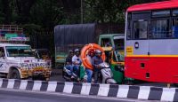 Bus safety A busy street scene in Bangalore showing various modes of transportation, including a scooter carrying three people, one of whom is holding a large orange coil. Surrounding vehicles include a bus, an auto rickshaw, and a decorated utility vehicle. The scooter riders and other commuters are all wearing helmets, depicting the typical urban traffic and diverse mobility options in the city. bengaluru,indien,karnataka