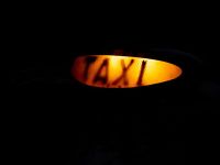 Taxi driver Illuminated orange London taxi sign, isolated on a black background. taxi,london,uk