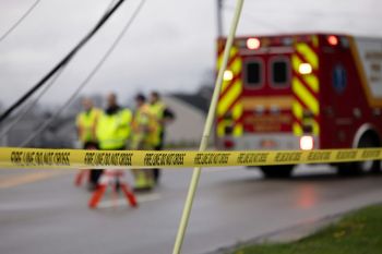 Violence Incident Emergency personnel behind “FIRE LINE DO NOT CROSS” tape near an ambulance.
