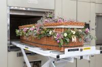 Funeral cremation A willow coffin decorated with flowers is moved into a cremator. cremation,funeral,behind the scenes