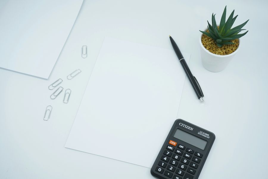 budget A financial and money themed photo featuring a blank paper on a desk next to a pen and calculator. Crunch the numbers! 