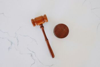 court A wooden gavel on a white marble backdrop. 