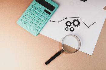 Finance audit magnifying glass on the desk with money. top view