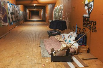 Homeless shelter A pedestrian underpass covered in colorful graffiti stretches into the distance in Braga, belongings of rough sleepers tucked against the orange-lit walls.