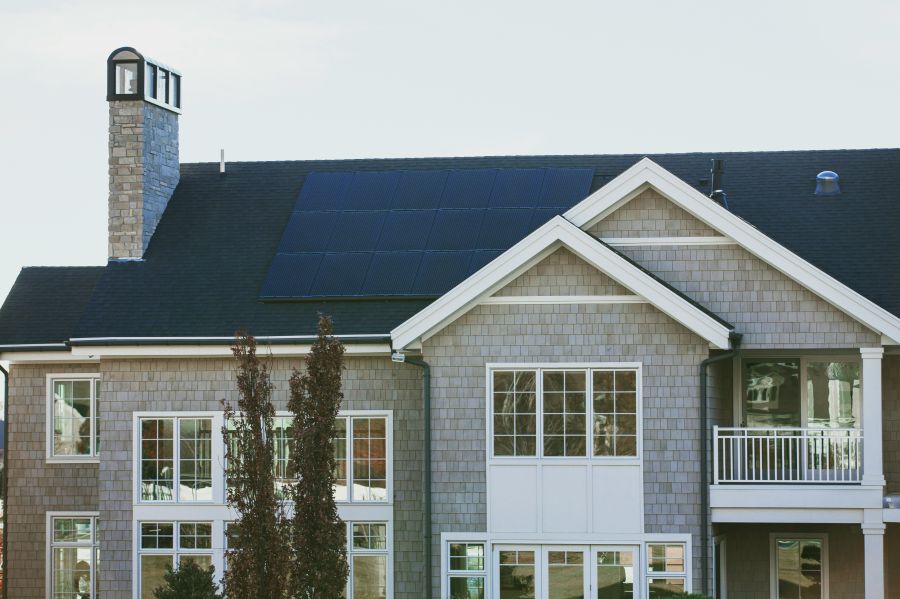 Energy renovation Vivint Solar - Solar Panels on a large seaside home with chimney and many windows.  