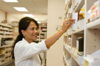 Pharmacies 	A female pharmacist is selecting a drug from the pharmacy inventory. medical,pharmacy,medical profession