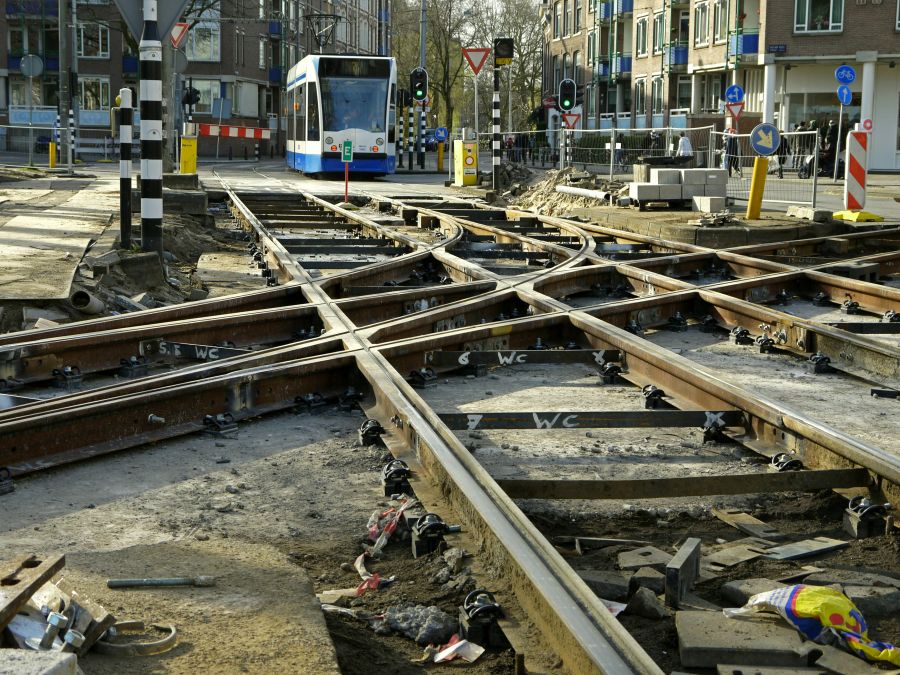 tram construction Photo of a city tram, arriving here at the location of tram track reconstruction; he has to stop for some minutes. This place is part of an important roundabout for tram-, bike- and car traffic in the old city-center of Amsterdam. Street photography of public transport by Fons Heijnsbroek, The Netherlands. 