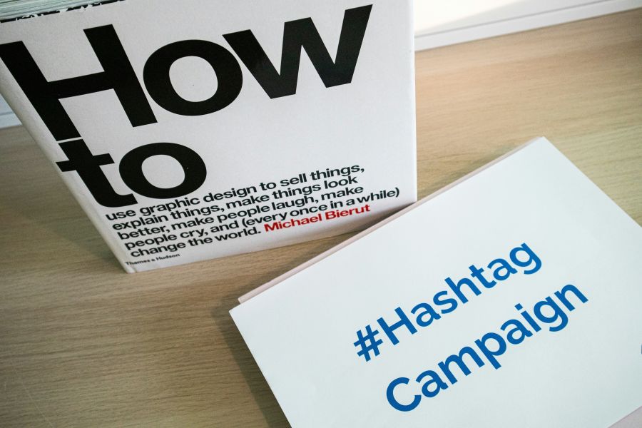 Campaign launch Desk with a "how to" book and a printed paper with the words #Hashtag Campaign on it 