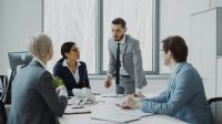 Bilateral meeting Businesswoman discussing reports with male and female colleagues sitting at the table in modern office indoors 