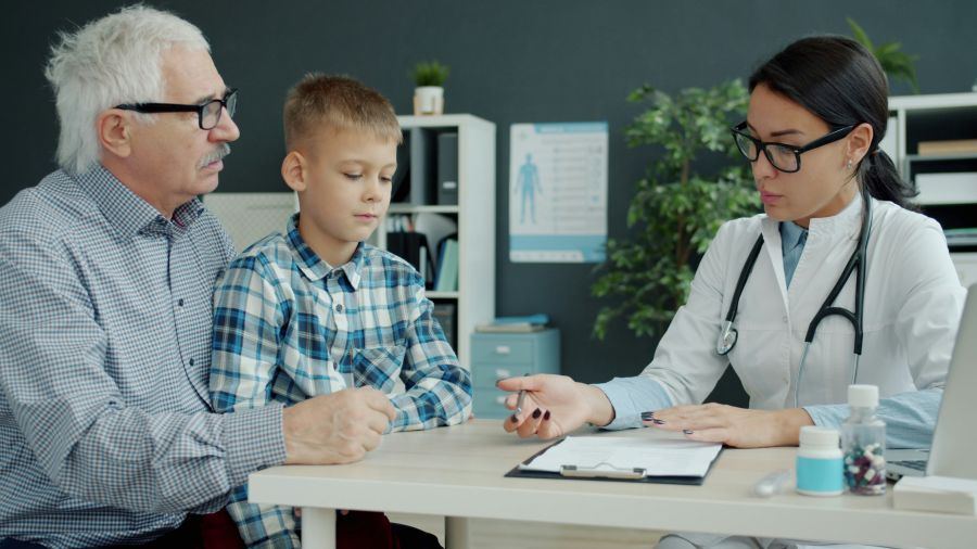 pediatrician shortage Female doctor is talking to caring grandfather and little grandson in office discussing child's health in hospital. Childhood, health and people concept. 