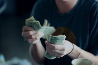 Fundraising Donation A twenty-four year old woman counting dollar bills. money,income,commercial