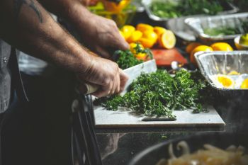 vegetarian chef Greens on a cutting board, and a Nice Knife and Lemons on the cutting board in the background