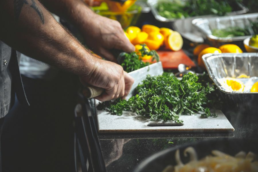 vegetarian chef Greens on a cutting board, and a Nice Knife and Lemons on the cutting board in the background 